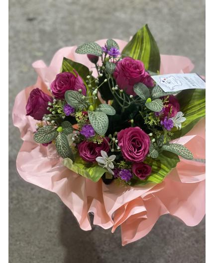Bouquet rond de fleurs artificielles avec des roses.